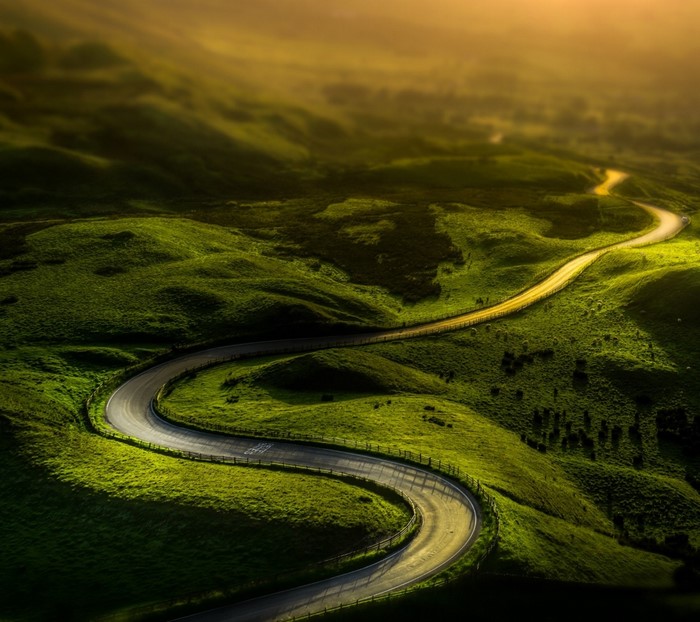 Winding road through green hills at sunrise