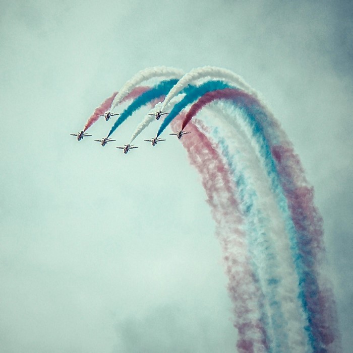 Airplanes performing aerobatics with red, white, and blue smoke