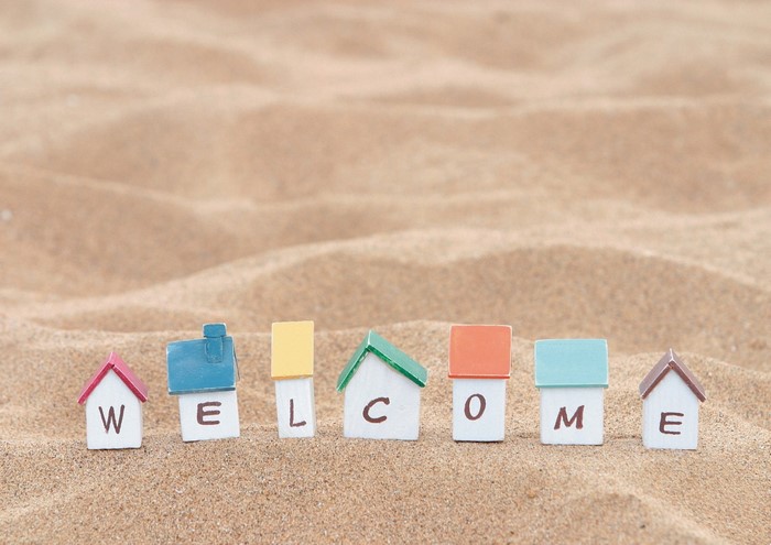 Miniature houses spelling WELCOME on sand