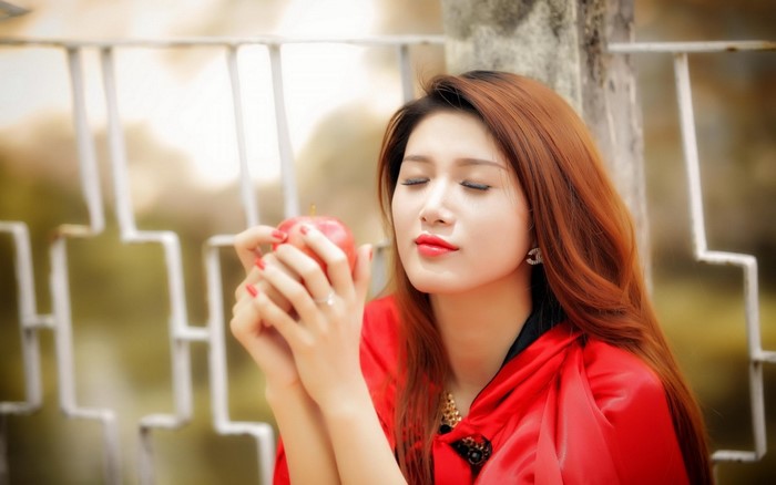 Asian woman in red holding an apple
