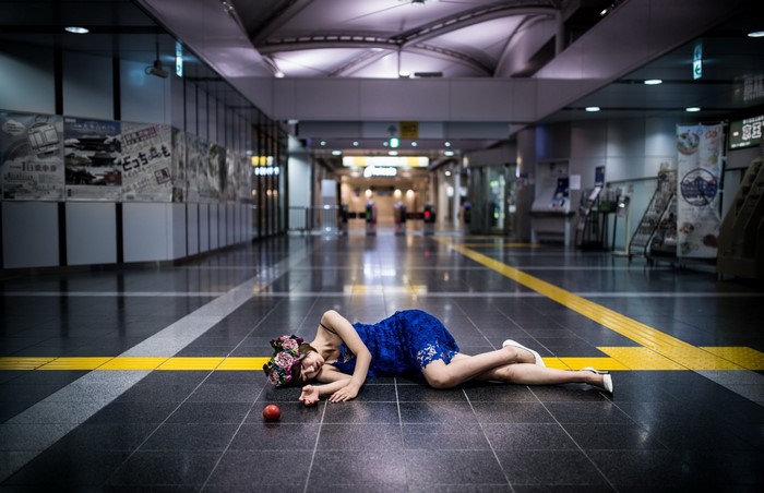 Woman in blue dress lying on train station floor