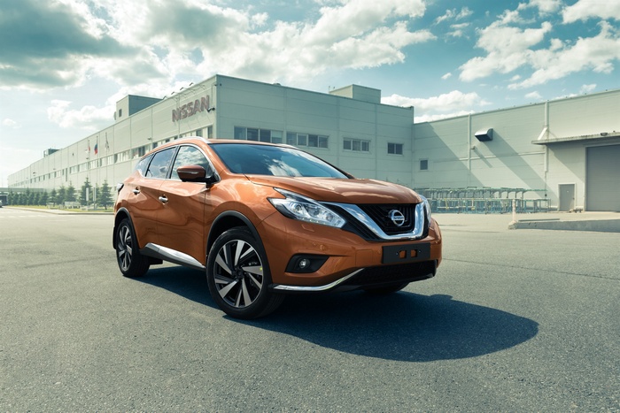 Orange Nissan Murano crossover in front of Nissan factory