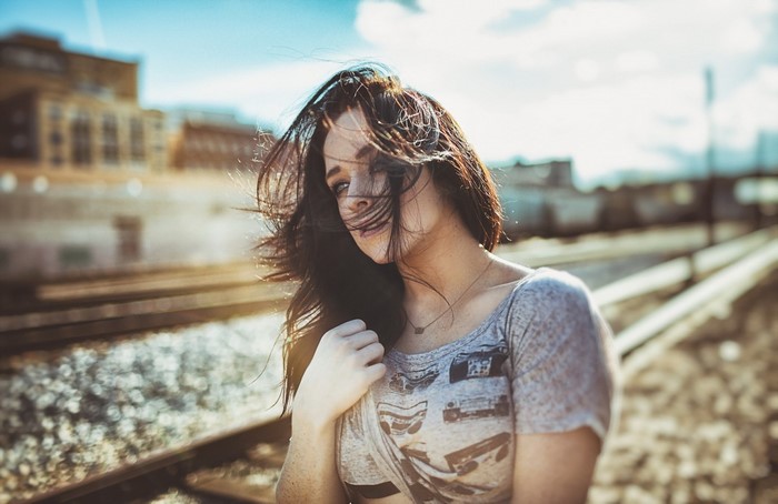 Woman with windblown hair on train tracks