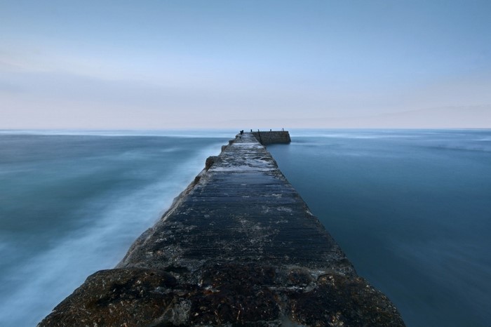 Concrete breakwater extending into the ocean at dusk