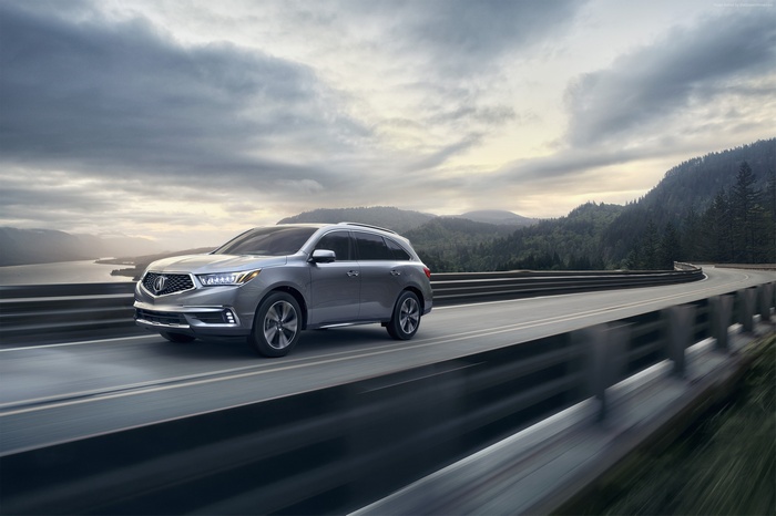 Silver Acura MDX SUV driving on a scenic road