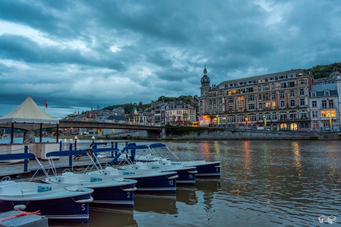 Boats docked on a river in Dinant, Belgium at dusk