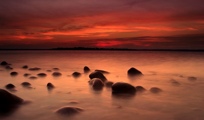Sunset over a rocky shore with calm water