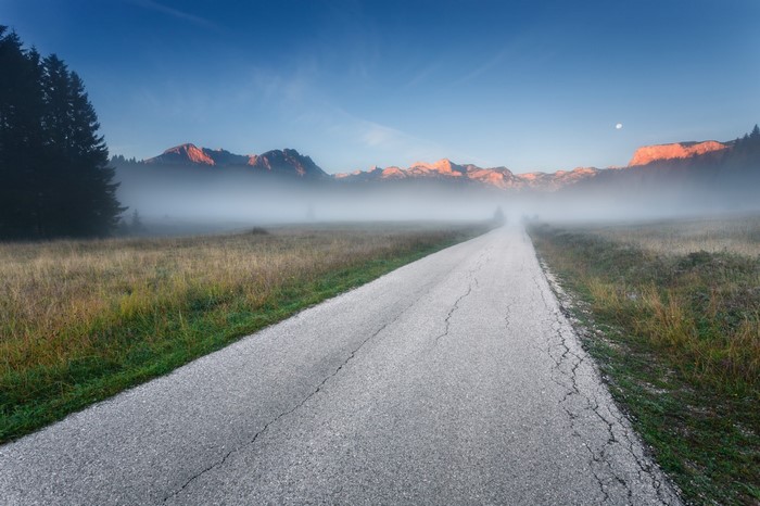 Road through misty mountains at dawn