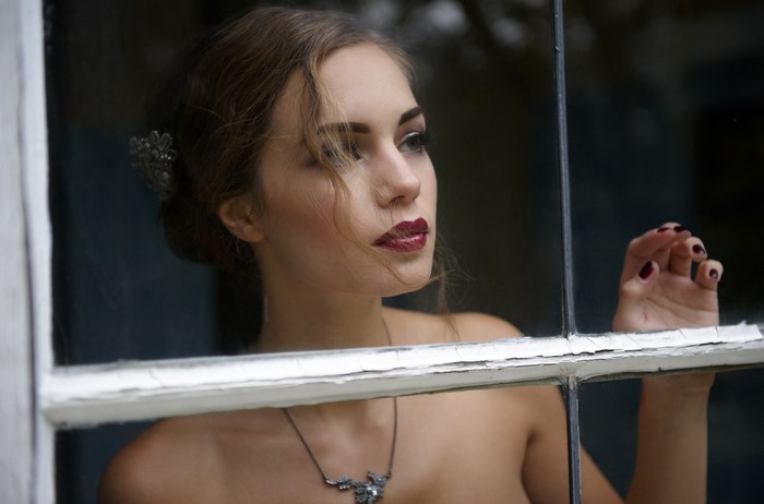 Woman with dark lipstick looking out a window