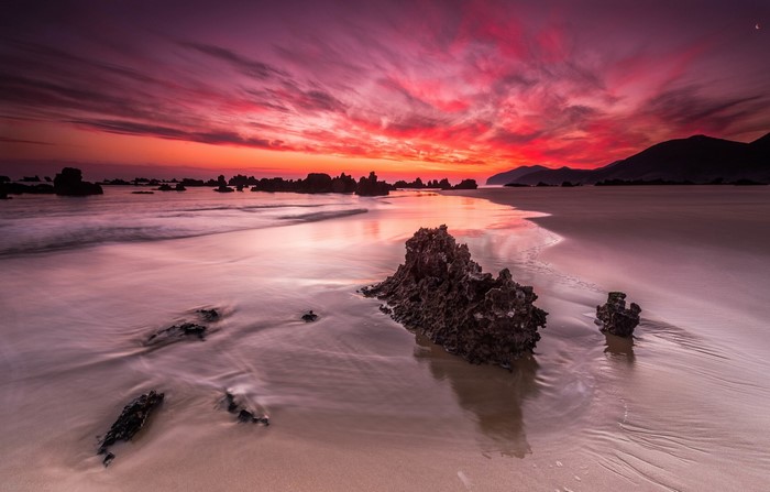Sunset over a rocky beach with colorful clouds