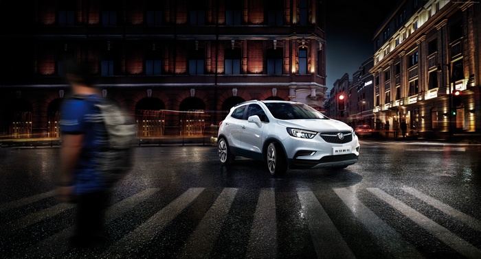 White Buick Encore crossover on a wet city street at night
