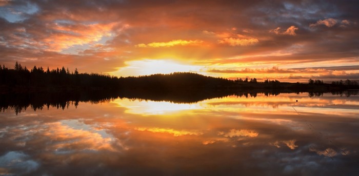 Sunset over a lake with forest reflection