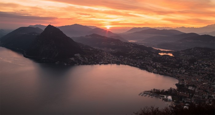 Sunset over mountains and lake with city