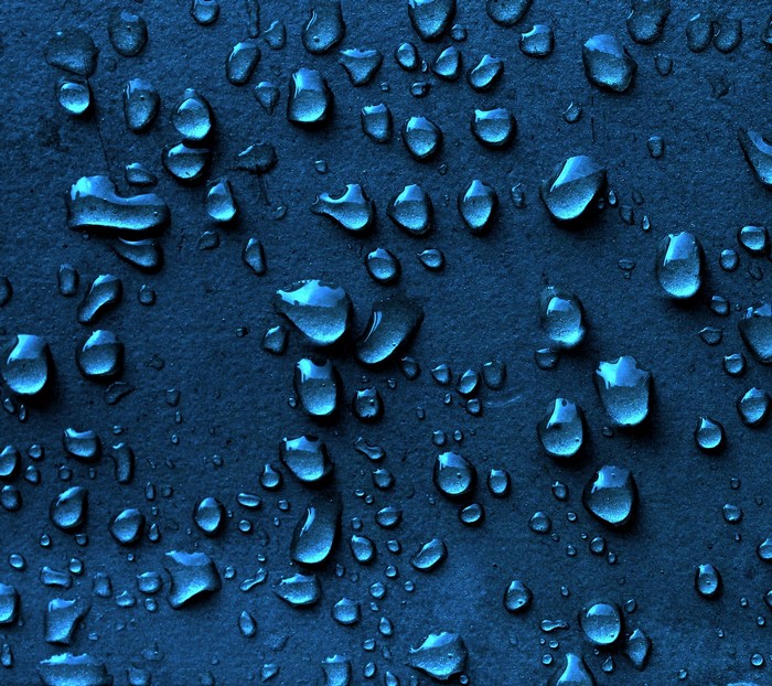 Close-up of water drops on a dark blue textured surface