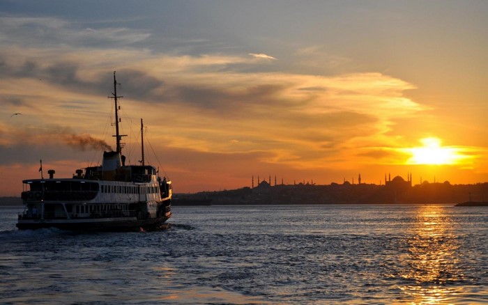 Ferry boat sailing on the sea at sunset with Istanbul skyline