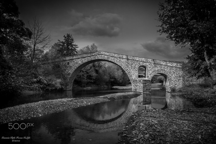 Stone bridge over a river in black and white