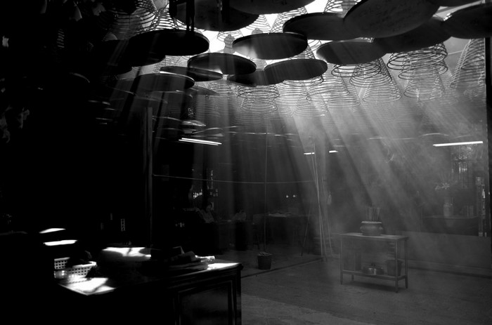 Sunbeams through incense coils in a dark interior