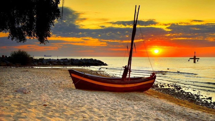 Boat on a beach at sunset over the sea