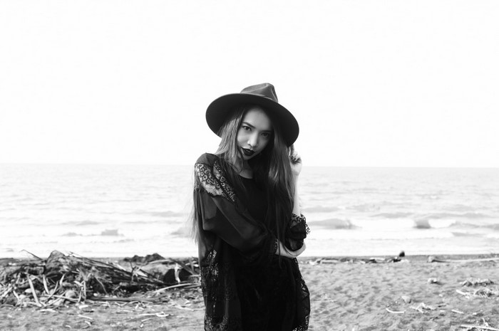 Woman in hat and black dress on beach