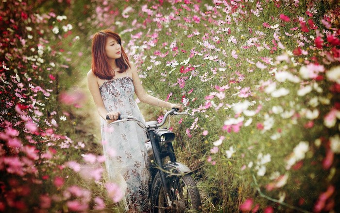 Woman with bicycle in a field of flowers