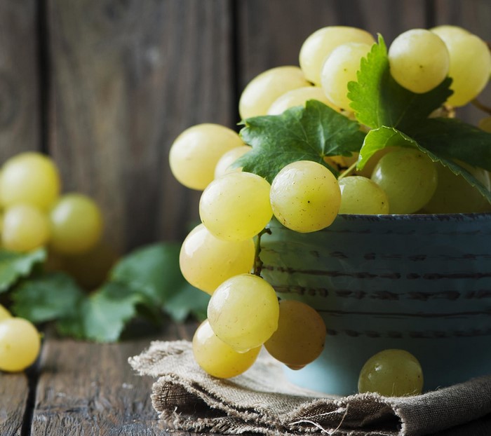 Green grapes in a blue bowl on a wooden table