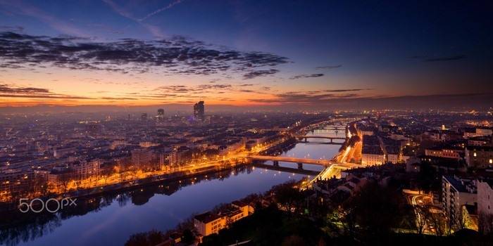 Cityscape of Lyon at sunset with river reflection