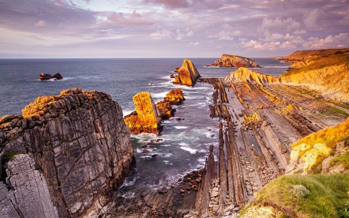 Rocky coastline at sunset with waves crashing