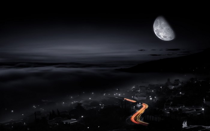 Night scene with moon over a foggy valley and city lights
