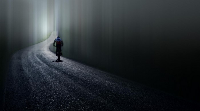 Bicyclist on a foggy road at night