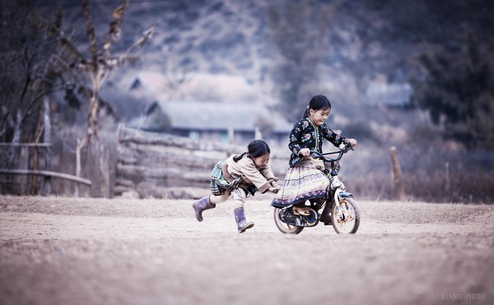 Two children playing with a bicycle outdoors