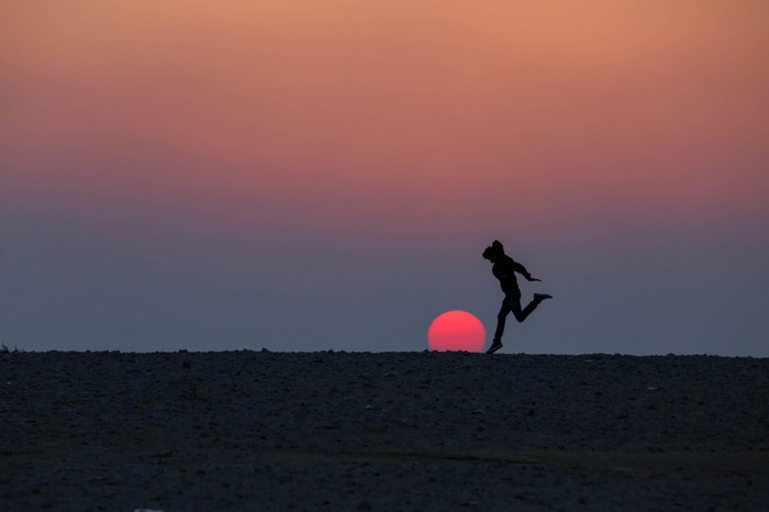 Silhouette of a person running at sunset