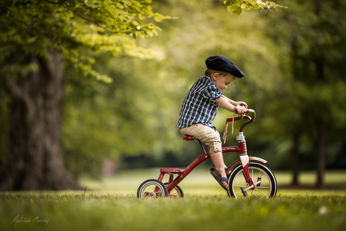 Boy on a red tricycle in a park