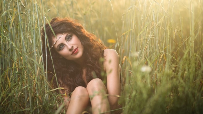 Woman with headband in a grassy field at sunset