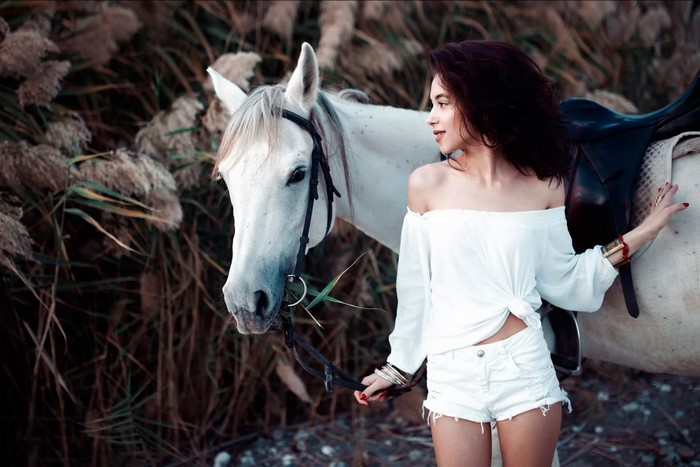 Woman in white outfit with a white horse