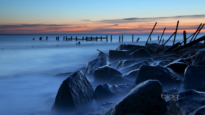 Ocean sunset with rocky shore and old pier remnants