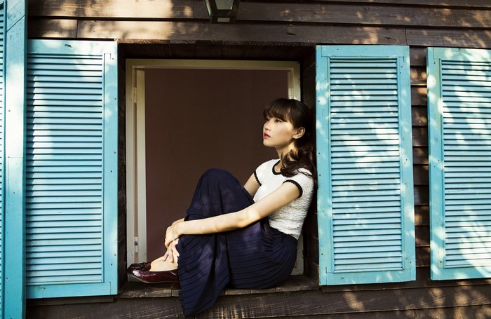 Woman sitting in a window with blue shutters