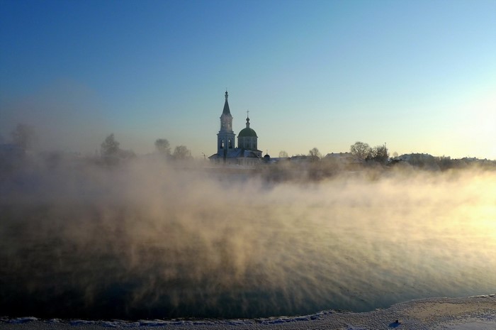 Church in mist over water at sunrise