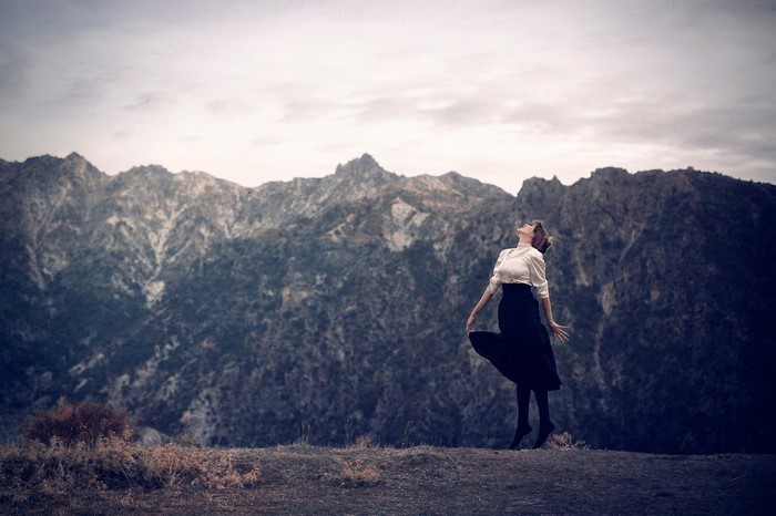 Woman in white shirt and black skirt dancing in mountains