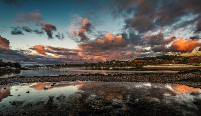Sunset over a calm sea with colorful clouds and reflections