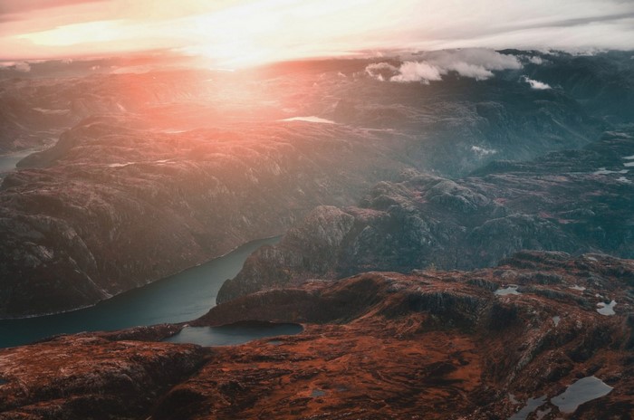 Aerial view of a fjord at sunrise with mountains and clouds