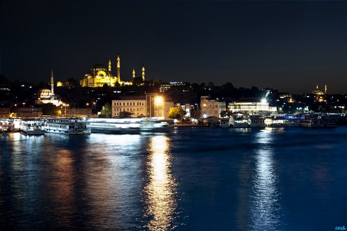 Cityscape at night with illuminated buildings and boats on the water
