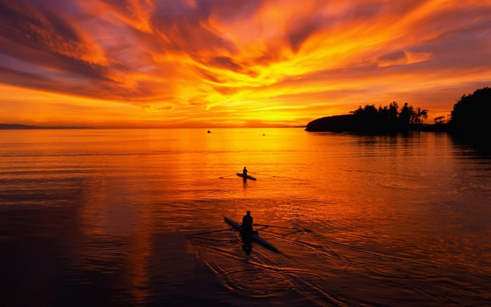 Two rowboats on the sea during a vibrant sunset