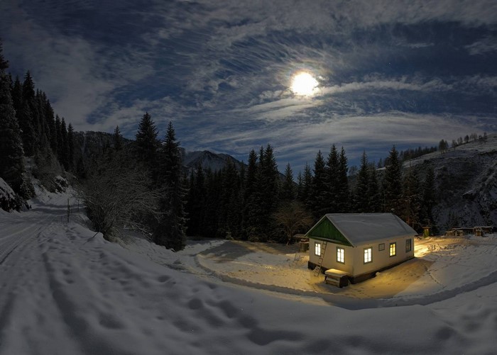 Snowy landscape with a house under the moonlight