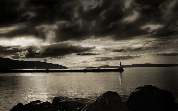 Monochrome lighthouse on a pier at sunset