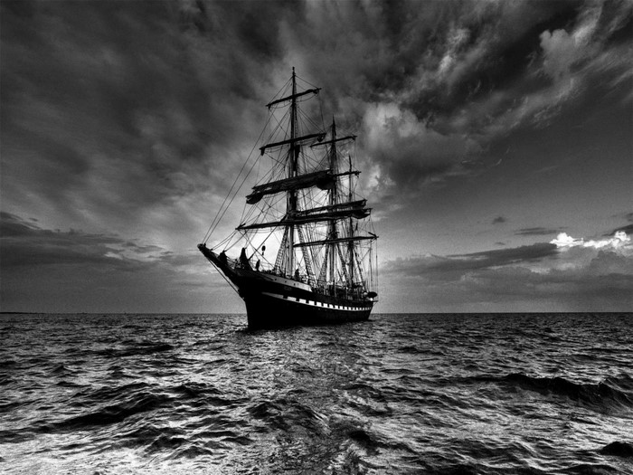 Tall sailing ship on a choppy sea under a cloudy sky