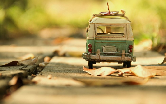 Toy van with surfboard on a path with leaves