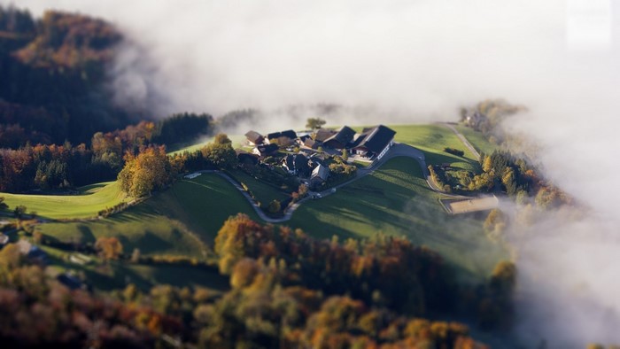 Village nestled in misty autumn mountains