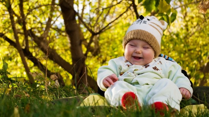 Baby in a hat sitting in grass