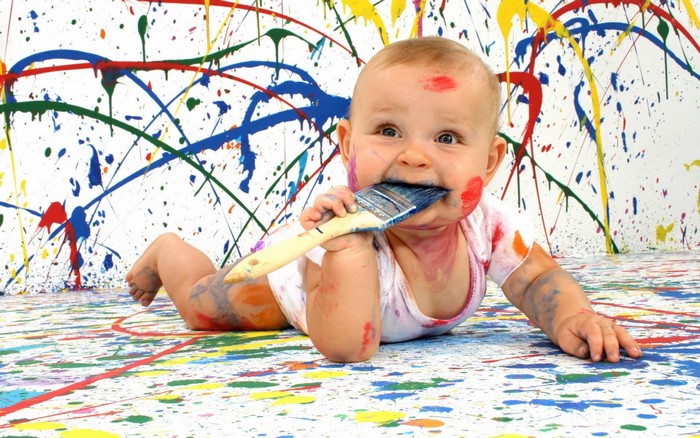 Baby playing with paint and paintbrush