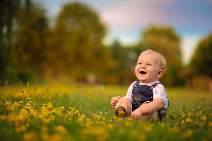 Baby sitting in a field of yellow flowers